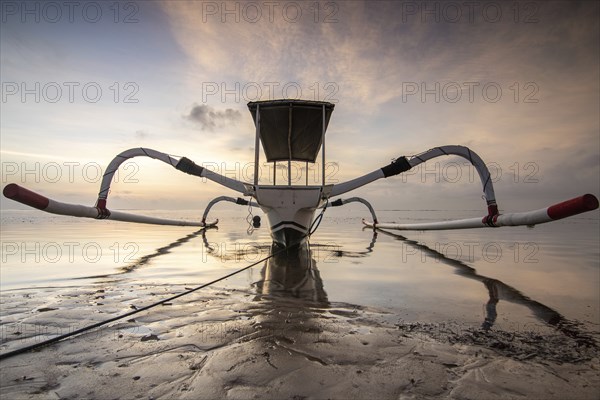 Fantastic sunrise on the beach with small temples and a traditional fishing boat, Jukung. View of