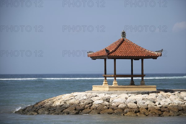 Fantastic sunrise on the beach with small temples and built as breakwaters. View of the sea as far
