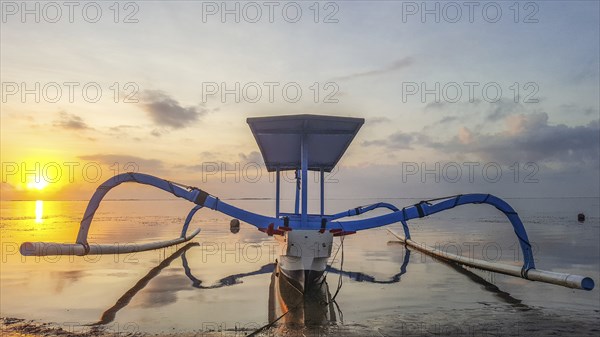 Fantastic sunrise on the beach with small temples and a traditional fishing boat, Jukung. View of