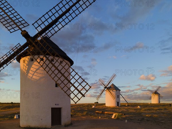 White windmills stand at sunset in an open landscape under a cloudy sky, windmills, Campo de