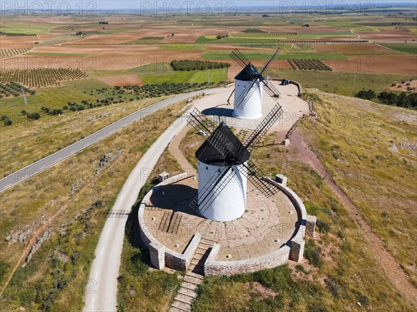 Aerial view of two white windmills with black roofs on a hill with roads and fields, aerial view,