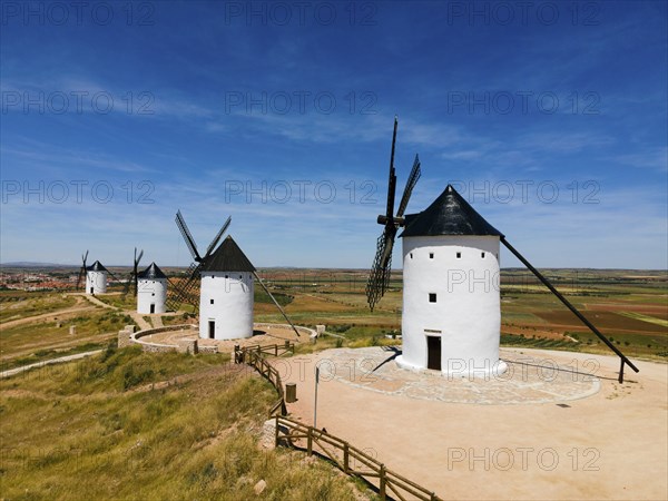 White windmills with black roofs standing in an expanse of fields and blue sky, aerial view,