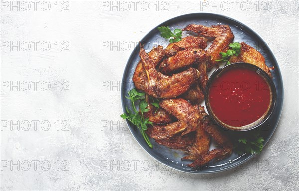 Fried in the oven, chicken wings, with spices, tomato sauce, on a plate, gray background, no