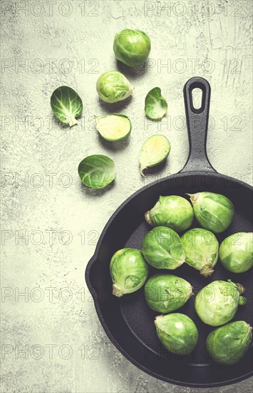 Fresh Brussels sprouts, raw, in a cast-iron pan, top view, on a gray table, no people