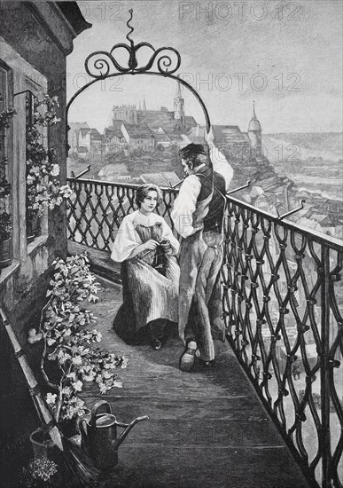 Couple standing on a balcony of the tower guard. A view of the city can be seen in the background,