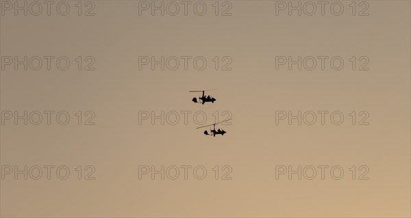 Two gyrocopters flying at sunrise, silhouettes against the morning sky, Mpumalanga, South Africa,