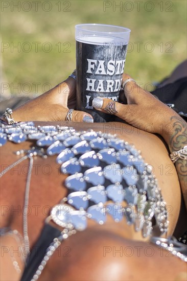 A festival visitor from Norway relaxes lying down with a Wacken cup in her hand at the Wacken Open
