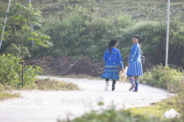 Two woman from the Hmong minority walk in everyday clothes on a street, Du Gia, Ha Giang province,