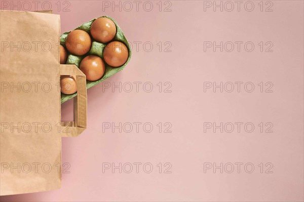 Kraft bag with chicken eggs in tray on beige background, shopping concept, space for text