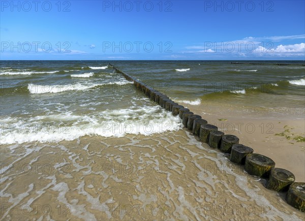 Sandy beach beach with wooden groyne in the Baltic Sea on the island of Usedom, clouds in the blue