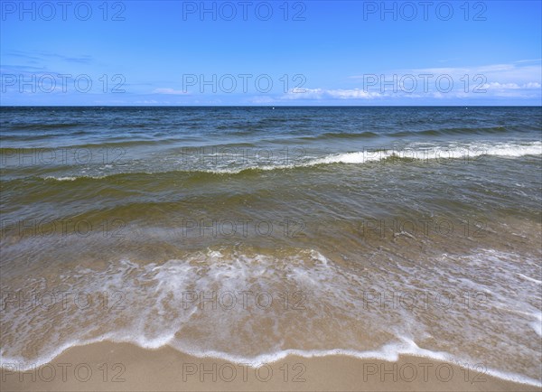Water flowing onto the sandy beach on the island of Usedom on the Baltic Sea under a blue sky with