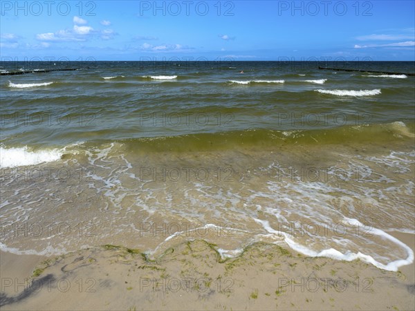 Water flowing onto the sandy beach on the island of Usedom on the Baltic Sea under a blue sky with