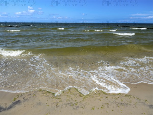 Water flowing onto the sandy beach on the island of Usedom on the Baltic Sea under a blue sky with