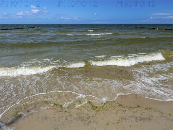 Water flowing onto the sandy beach on the island of Usedom on the Baltic Sea under a blue sky with