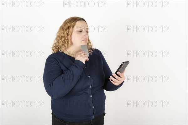 Woman shopping online holding her phone and credit card