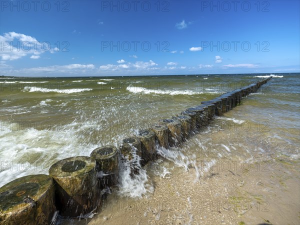 Spray splashes on a wooden groyne on a sandy beach on the Baltic Sea on the island of Usedom,