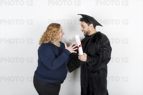 Recent graduate man, dressed in cap and gown, showing off his degree celebrating with his family