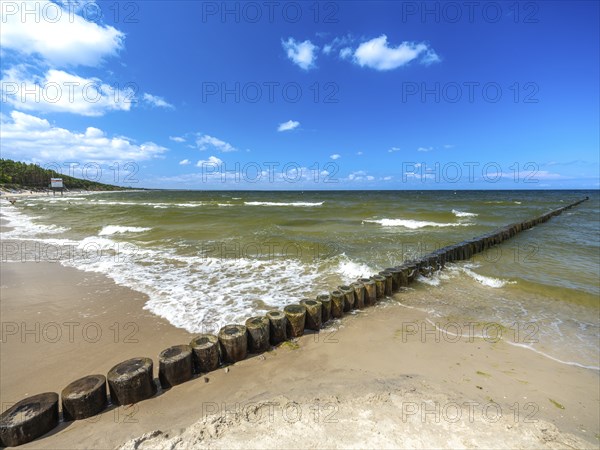 Sandy beach beach with wooden groyne in the Baltic Sea on the island of Usedom, clouds in the blue