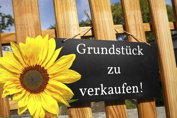Sign with the inscription GRUNDSTÜCK ZU VERKAUFEN on a wooden fence (symbolic image)