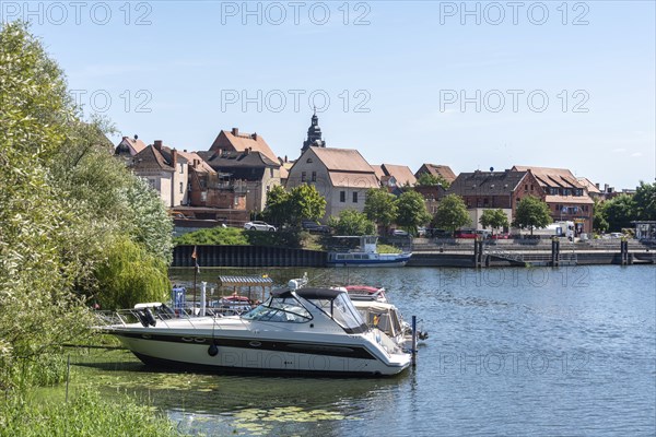 A boat is anchored, behind it parts of the old town centre of Havelberg, Saxony-Anhalt, Germany,
