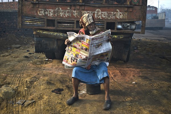 Muslim man reading the newspaper in the street (Dhanbad, Jharkhand, India) . The newspaper is