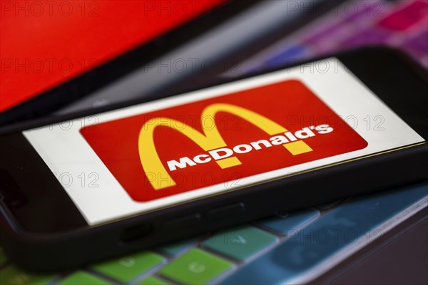 In this photo illustration, McDonald's logo is displayed on a smartphone with a laptop display