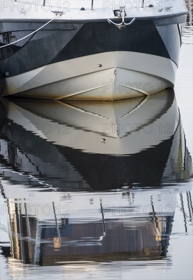 The bow of a ship is reflected in the Tanger river at the harbour at the mouth of the Elbe,