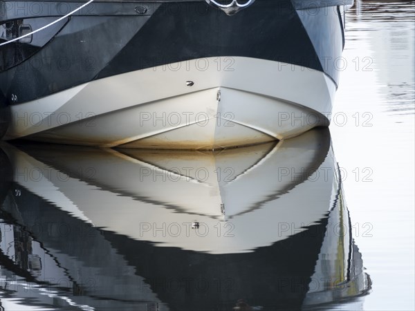 The bow of a ship is reflected in the Tanger river at the harbour at the mouth of the Elbe,