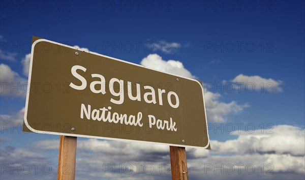 Saguaro national park (arizona) road sign against blue sky and clouds