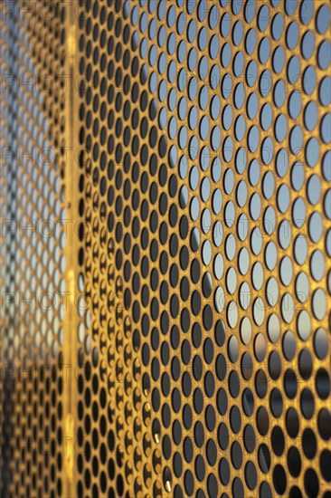 Aluminum composite panels or cladding with perforated sheets on modern building facade on sunset,