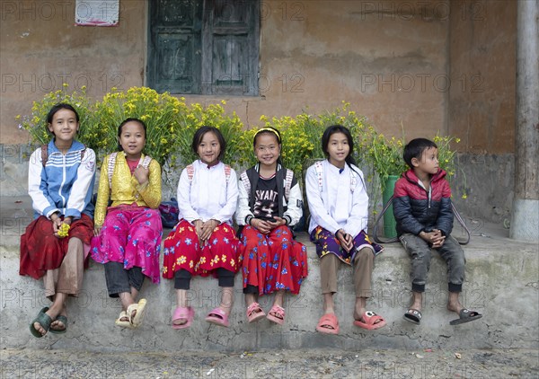 Vietnamese girls with baskets of flowers on their backs sitting on a ledge, Lungcam Cultural
