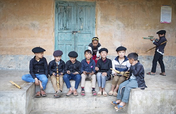 Vietnamese boys in traditional clothes and with traditional flutes playing with their mobile