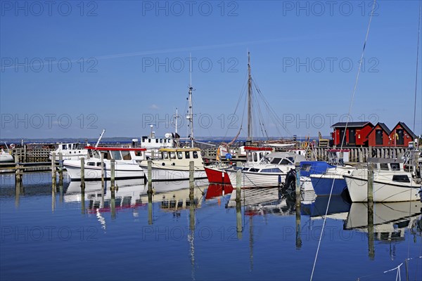 Boats in the harbour are reflected in the calm water under a bright blue sky, Herrenhausroute,