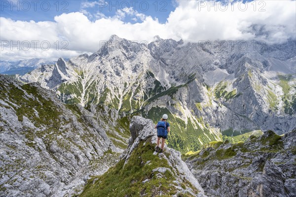 Mountaineer climbing Waxenstein, Alpspitze Wetterstein range in the background,
