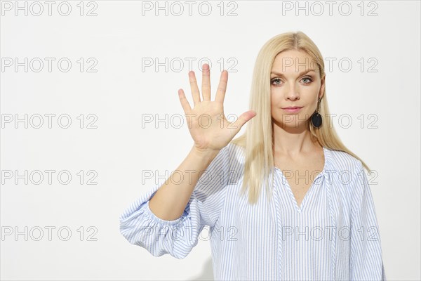 Attractive blonde woman shows five fingers. Counting with fingers