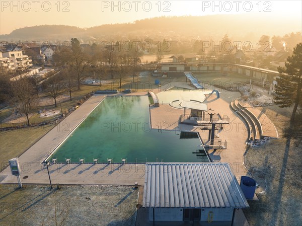 View of a swimming pool with slides and nearby residential buildings in the morning sun and frozen