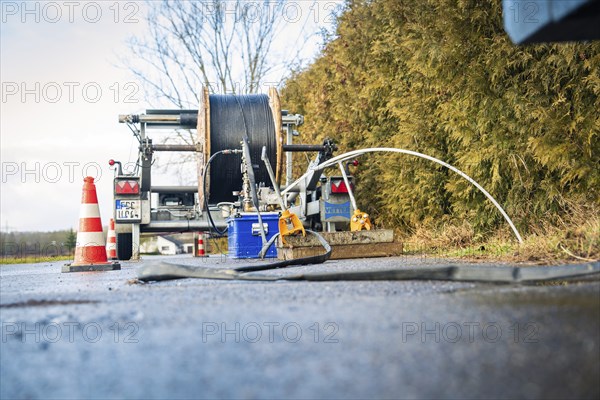 Road work equipment with wet surface and cable reel in the foreground, fibre optic construction,