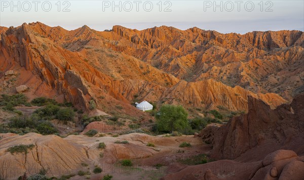 Yurt between red rocks, canyon of eroded sandstone formations, red and orange sandstone rocks,