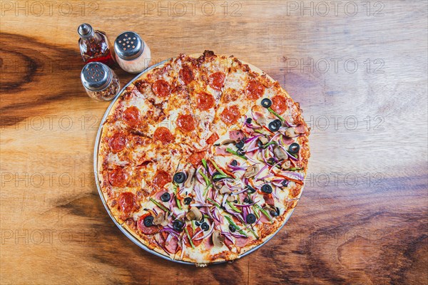 Top view of a supreme mixed pizza on wooden table. High angle view of mixed supreme pizza on wooden