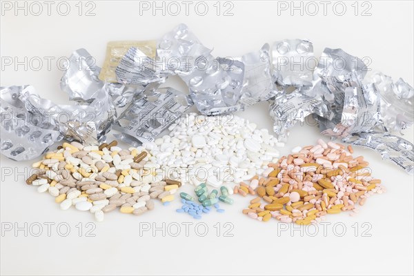 Empty blister packs with tablets of different colours and shapes, white background