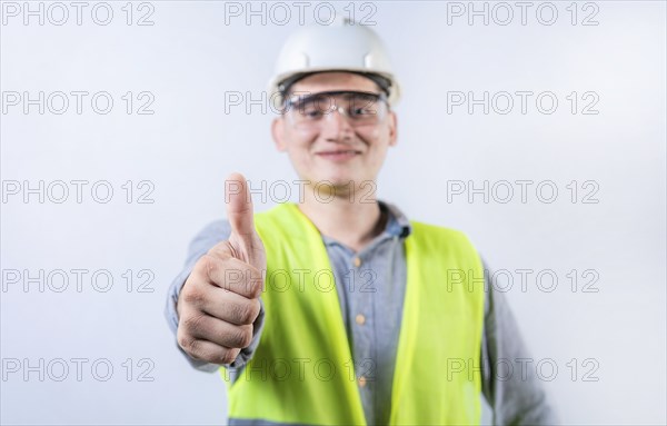 Smiling young engineer gesturing approval with thumb. Cheerful engineer giving thumbs up to the