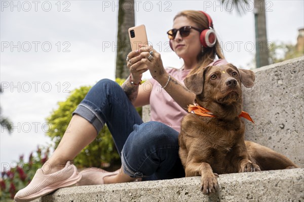 Close-up of an adorable dog attentively gazing at the horizon while sitting next to its owner, who