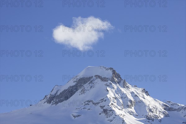 White cloud over snow covered mountain top, pinnacle Ciarforon in winter in the Gran Paradiso