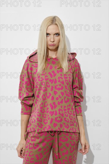 Upset, sad woman in pink pyjama on white background