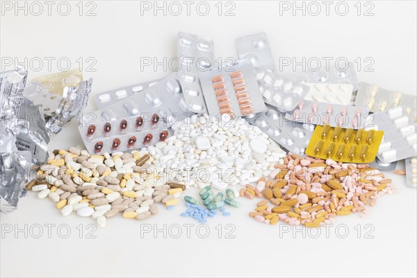 Empty and full blister packs with tablets of different colours and shapes, white background