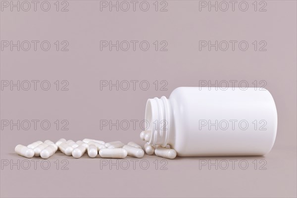 Medical capsule pills spilling from blank container