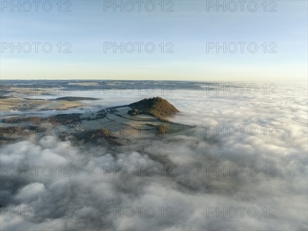 Aerial view of the wintry and fog-covered Hegaulandschaft shortly after sunrise, the volcanic cone