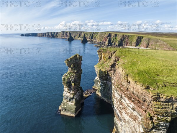 Aerial view of the rugged coastal landscape at Duncansby Head with rock tower, behind it the