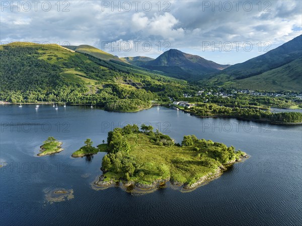 Aerial view of the island of Eilean Munde, behind it the village of Ballachulish with the harbour