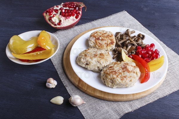 Meatballs with rice mushrooms, sweet peppers and pomegranate seeds on black wooden background.